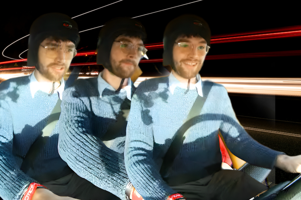Three men wearing black racing helmets sit shoulder-to-shoulder in a moving vehicle, gripping the wheel and smiling as red and white light trails streak behind them, emphasizing motion and acceleration.