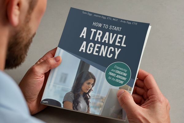 Close-up of “How to Start a Travel Agency” book in hand highlighting the fully rewritten edition for modern travel advisors