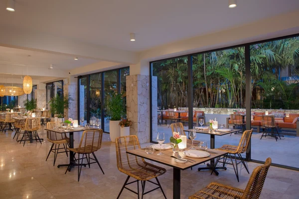 Bloom restaurant at Zoetry Curacao with elegant indoor and outdoor dining areas framed by tropical palms