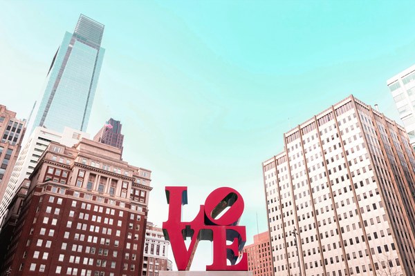 The iconic red LOVE sculpture by Robert Indiana in Philadelphia's JFK Plaza framed by city skyscrapers, a stop on the American Stories Travel multi-destination journey