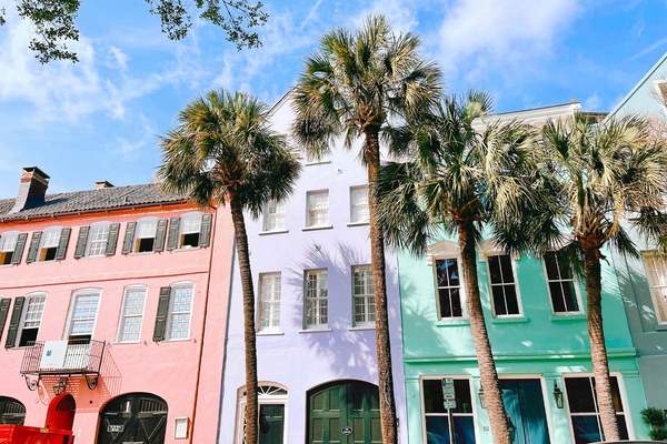 Pastel pink, purple, and mint Rainbow Row houses framed by palmetto palms in historic Charleston, South Carolina, part of the American Stories Travel Southern itinerary