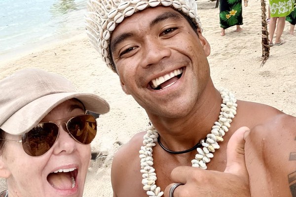 Kim Ferri Watkins, Cruise Planners franchise owner, smiling with a local performer at the 2026 Elite Summit beach event in Tahiti