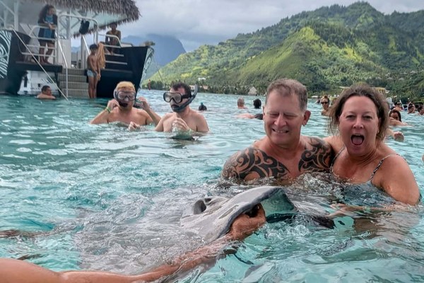 Debra and Tony Thune, Cruise Planners franchise owners, swimming with a stingray on a snorkel excursion off Moorea in Tahiti