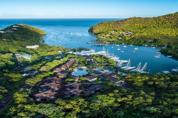 Aerial view of Zoëtry Marigot Bay nestled into the hillside above the marina with anchored yachts and lush green peaks in St. Lucia