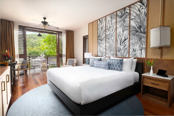 Caribbean-chic suite at Zoëtry Marigot Bay with palm-print accent wall, hardwood floors, and balcony overlooking the marina