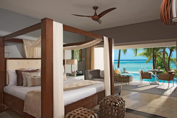 Luxurious canopy four-poster bed suite at Zoëtry Montego Bay with ocean view balcony and Caribbean palms beyond