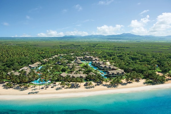 Aerial view of Zoëtry Agua Punta Cana showing thatched-roof villas, lush palms, and the white sand beach of Uvero Alto in the Dominican Republic