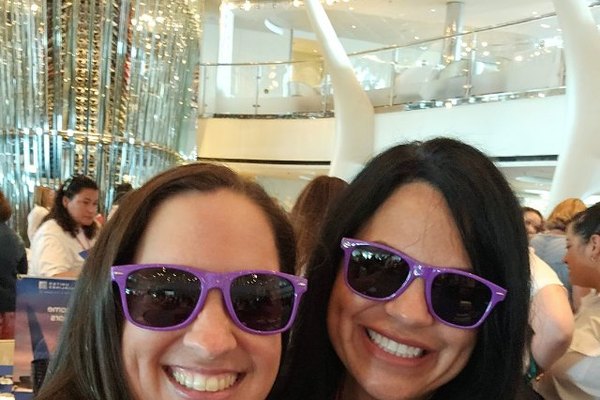 Two Nexion Travel Group advisors smiling in matching purple sunglasses at a coneXion networking event