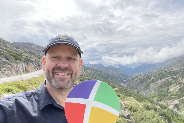 A Nexion Travel Group advisor holding the colorful Nexion X paddle on a scenic mountain overlook during a trip