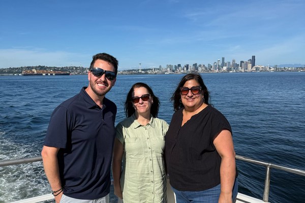 Three travel advisors aboard a boat with the Seattle skyline and Space Needle in the background at a Travel Leaders Network event