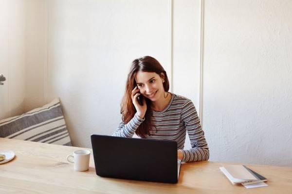 A travel advisor smiles while speaking with a client by phone