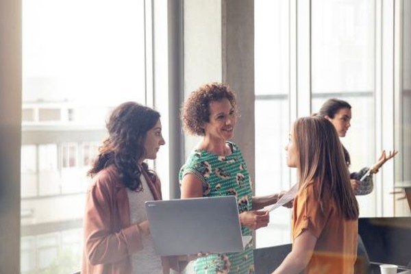 Three travel advisors collaborate near a bright office window